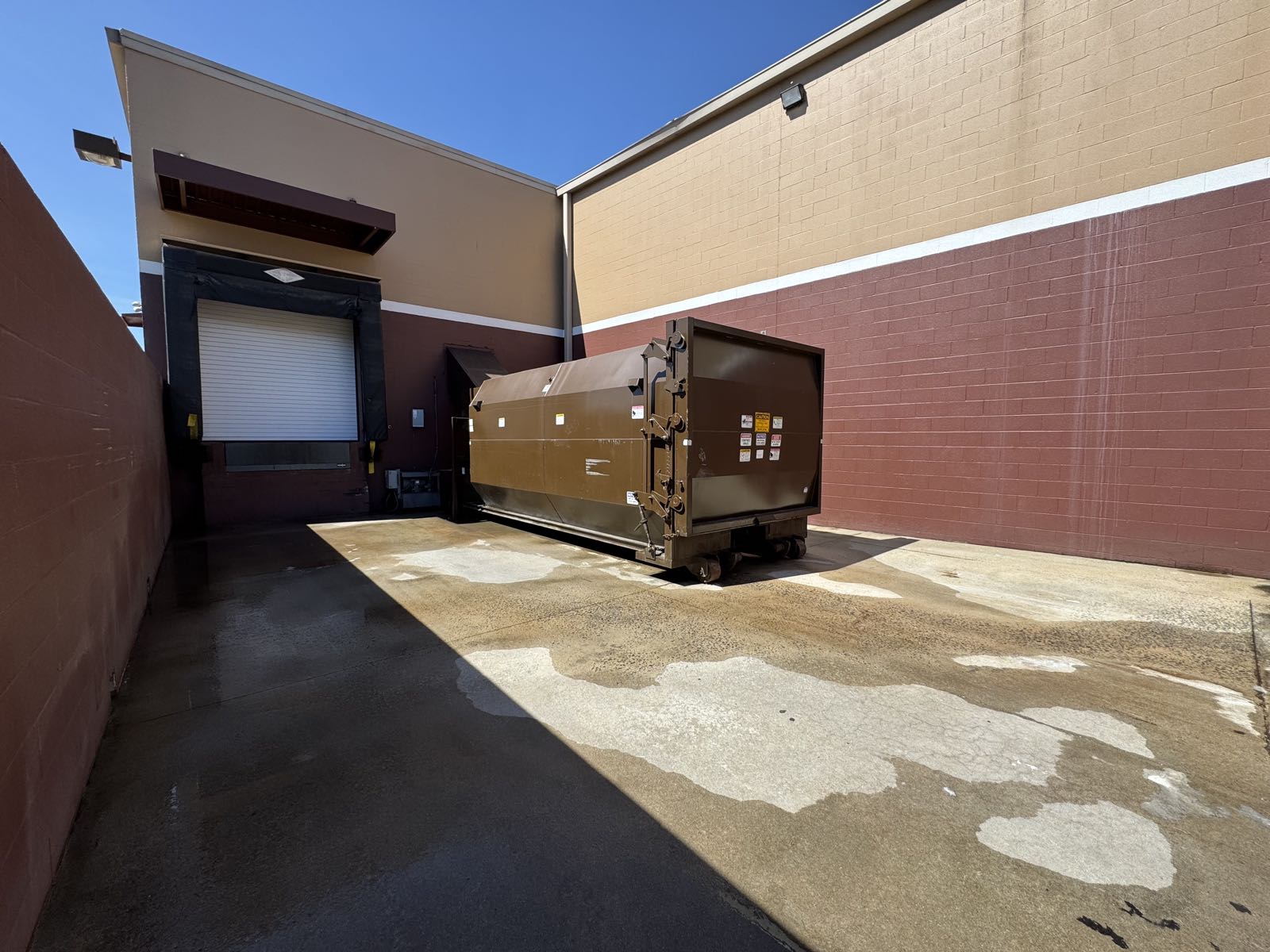 Trash compactor and loading dock area freshly pressure washed and degreased at a commercial property in North Carolina